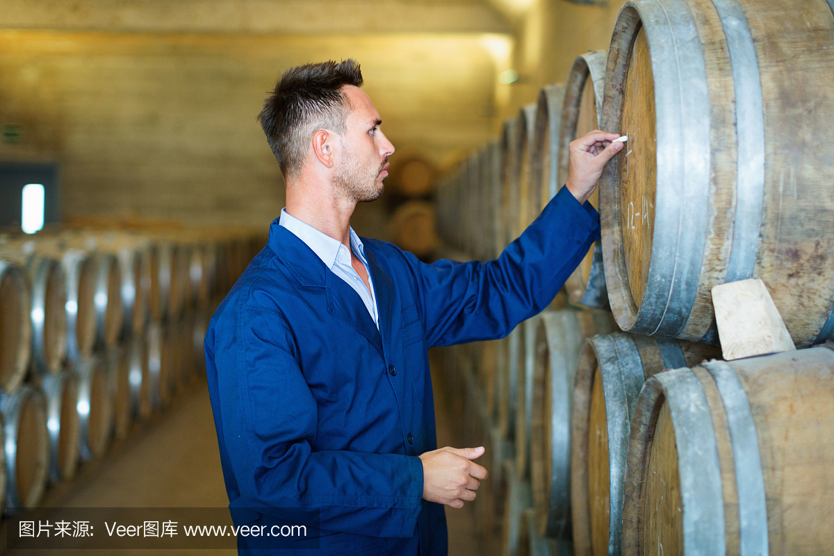 穿外套的年輕人在記錄葡萄酒工廠